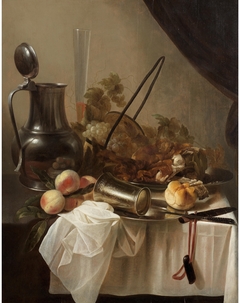 A pewter jug with an overturned silver cup with fruit, bread and meat on a draped table-top by Cornelis Kruys